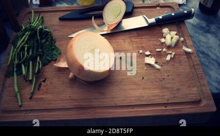 Preparazioni alimentari, tagliere in legno con coltello alle erbe fresche sull'isola della cucina. Foto Stock