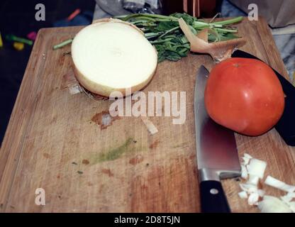 Preparazioni alimentari, tagliere in legno con coltello alle erbe fresche sull'isola della cucina. Foto Stock