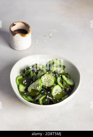 ciotola con insalata di cetrioli alle alghe wakame su sfondo grigio. Foto Stock