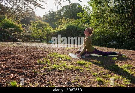 Donna bionda, quaranta anni pratica yoga pone in un ambiente esterno, Londra, Inghilterra Foto Stock
