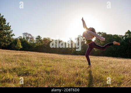 Donna bionda, quaranta anni pratica yoga pone in un ambiente esterno, Londra, Inghilterra Foto Stock