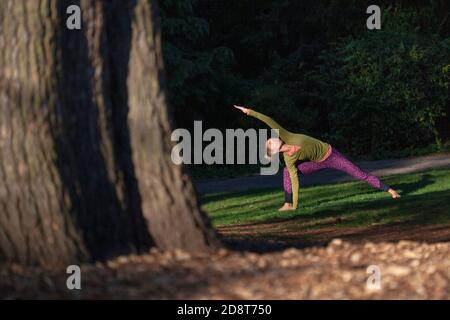 Donna bionda, quaranta anni pratica yoga pone in un ambiente esterno, Londra, Inghilterra Foto Stock