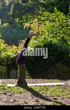 Donna bionda, quaranta anni pratica yoga pone in un ambiente esterno, Londra, Inghilterra Foto Stock