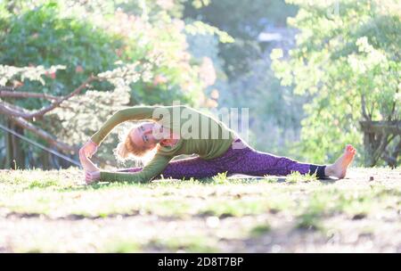 Donna bionda, quaranta anni pratica yoga pone in un ambiente esterno, Londra, Inghilterra Foto Stock
