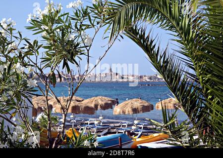 Skyline di Alghero dietro un giardino vicino alla spiaggia Foto Stock