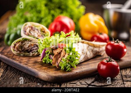Tortilla con carne e insalata con più tortillas ripieni e. pomodori sul lato Foto Stock