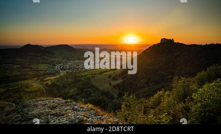 Germania, Vista panoramica sulla verde valle dell'alb sveva Schwäbische Alb paesaggio naturale e rovine del castello di hohenneuffen su una montagna in caldo tramonto l Foto Stock