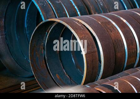 Contesto industriale senza persone. I tubi metallici di grande diametro sono tagliati in anelli. Foto Stock
