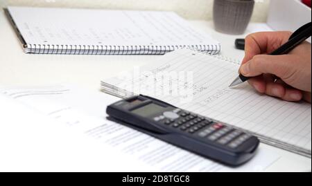 Lo studente risolve le formule matematiche. L'uomo scrive con una penna in un notebook. Compiti. Note in un notebook. Foto Stock