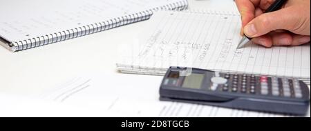 Lo studente risolve le formule matematiche. L'uomo scrive con una penna in un notebook. Compiti. Note in un notebook. Foto Stock