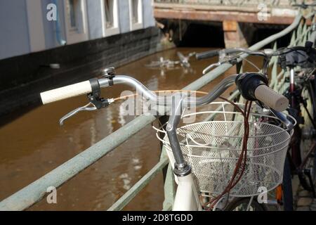 Una vecchia bicicletta d'epoca appoggiata su una ringhiera metallica lungo un ruscello cittadino di Friburgo in Germania chiamato Baechle. C'è un flusso in background. Foto Stock