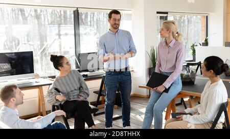 Diversi giovani uomini d'affari motivati dalla multirazziale che ascoltano il leader. Foto Stock
