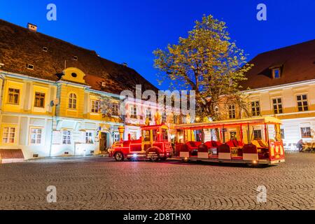 Sighisoara, Romania. Piazza della città vecchia e treno turistico. Foto Stock