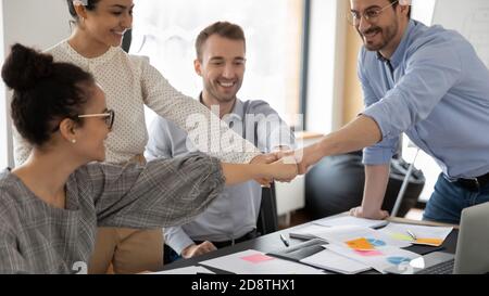 Felice millennial variegata gente d'affari multirazziale che batte i pugni. Foto Stock
