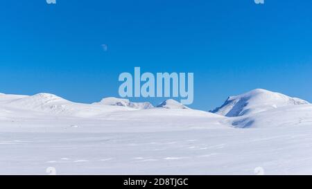 Montagne in inverno con la luna piena in aumento nel Parco Nazionale di Rondane, Norvegia Foto Stock