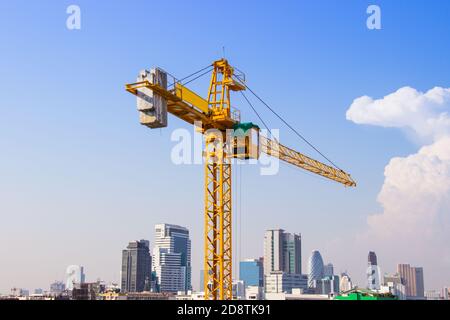 La gru viene utilizzata nella costruzione di edifici alti per utensili di grandi industrie sotto il cielo blu e le nuvole bianche. Foto Stock