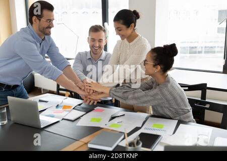 Motivati giovani compagni di squadra di gara misti che mettono insieme le mani. Foto Stock