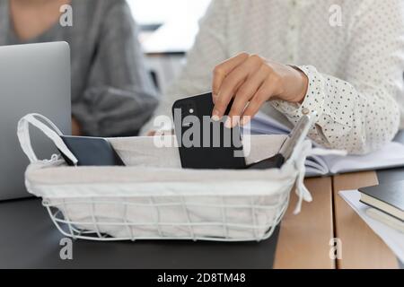 Primo piano giovane donna che mette smartphone in scatola con i gadget. Foto Stock