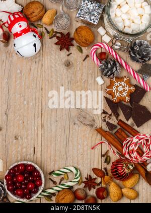 Sfondo culinario natalizio di noci (nocciole, noci, mandorle), spezie (cannella, anice stellato, chiodi di garofano, cardamomo), cioccolato, caramello, mirtilli rossi, Foto Stock