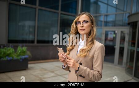 Sorridendo bella donna d'affari utilizzando il suo telefono cellulare Foto Stock