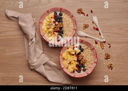 Spuntini sani in ciotola: Yogurt, fiocchi d'avena, mela, mirtilli, noci, goji e semi di chia. Supercibo. Concetto di alimentazione sana, stile di vita sano Foto Stock