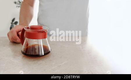 Versare, V60. Caffè appena preparato in un server di vetro sul tavolo. Foto Stock