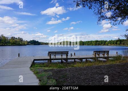 Molo vuoto con panchine che si affacciano su un lago sotto il cielo blu Foto Stock