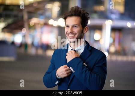 Ritratto di un imprenditore sorridente adegua la sua cravatta Foto Stock