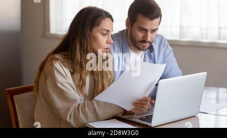 Coppia di famiglia millennial pensive che studia le fatture di carta in ufficio domestico Foto Stock