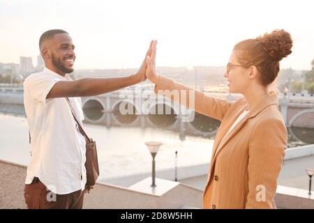 Sorridenti partner commerciali di varie etnie che si danno un altro alto cinque Foto Stock