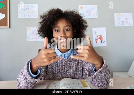 Ragazza capretto sorda africana che mostra il gesto della lingua del segno guardando la macchina fotografica. Foto Stock