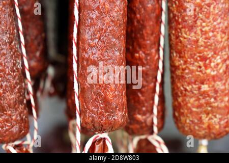 Bastoncini di salsiccia sono appesi nel negozio. Produzione e vendita di prodotti a base di carne Foto Stock