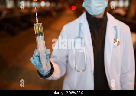 Ritratto corto di veterinario femminile che tiene grande siringa witjh medicina mentre vaccinare le mucche e il bestiame in fattoria, copia spazio Foto Stock