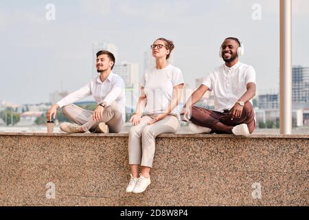 Gruppo di giovani sereni e rilassati lavoratori collari bianchi meditando a pausa Foto Stock