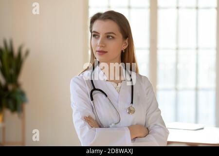Medico fiducioso e premuroso in carica guardando da parte la decisione di pianificazione Foto Stock