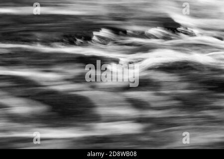 Vista dettagliata dell'acqua fluente di un piccolo fiume, immagine in bianco e nero ad alto contrasto, strutture fluenti, lunga esposizione Foto Stock