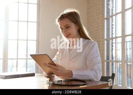 Medico amichevole che consulta il paziente online da videocall utilizzando tablet pc Foto Stock