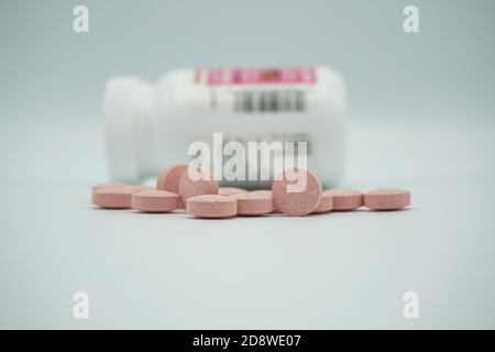 Pillole di vitamina di medicina farmaceutica ha versato fuori da una bottiglia, su sfondo grigio. Spazio di copia per il testo. Foto Stock