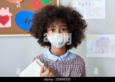 Scuola africana bambina ragazza indossando maschera in classe, headshot ritratto. Foto Stock
