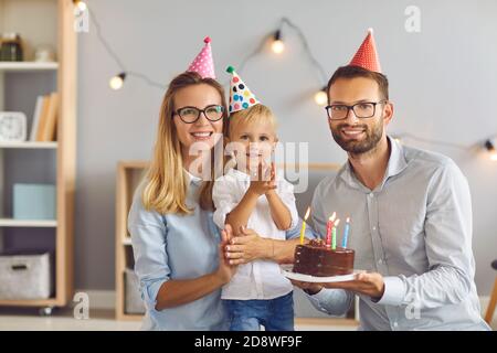 Ritratto dei genitori felici e del loro bambino di compleanno a. casa guardando la macchina fotografica e sorridendo Foto Stock