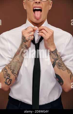 Grimacing elegante donna d'affari di mezza età in camicia bianca che mostra la lingua Foto Stock