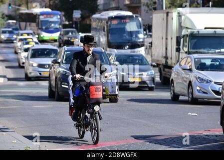 Hasidic uomo su una bicicletta nel traffico di Gerusalemme Foto Stock