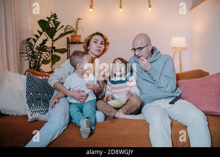 La famiglia guarda la televisione insieme sul divano nel soggiorno camera Foto Stock