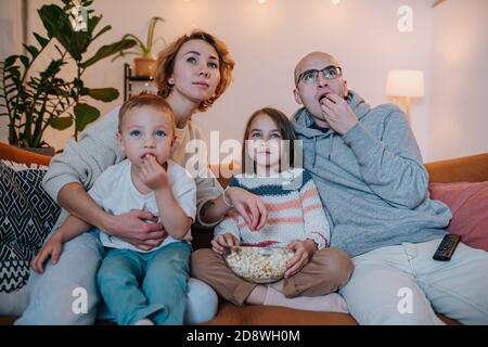 La famiglia guarda la televisione insieme sul divano del soggiorno Foto Stock