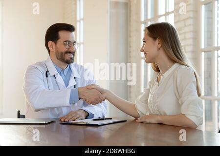 Giovane donna paziente handshaking con medico di sesso maschile firma polizza di assicurazione Foto Stock