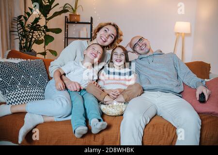 Una famiglia gioiosa che guarda la commedia insieme sul divano nel soggiorno Foto Stock