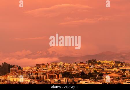 Skyline di Quito durante un tramonto arancione con il vulcano Cayambe sullo sfondo, Andes montagne, Ecuador. Foto Stock