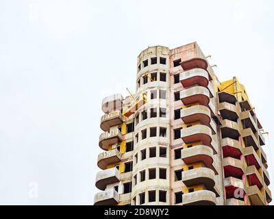 Alto edificio in costruzione con balconi arrotondati e una culla in cima. CopySpace Foto Stock