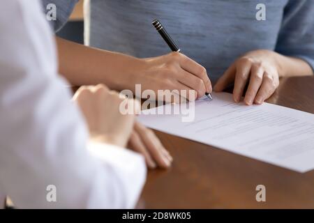 Primo piano della giovane donna candidata al lavoro che firma il contratto di lavoro Foto Stock