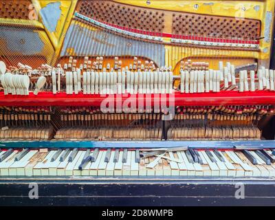 Un frammento di un vecchio pianoforte rotto con un muro mancante e tasti rotti. Vista frontale Foto Stock